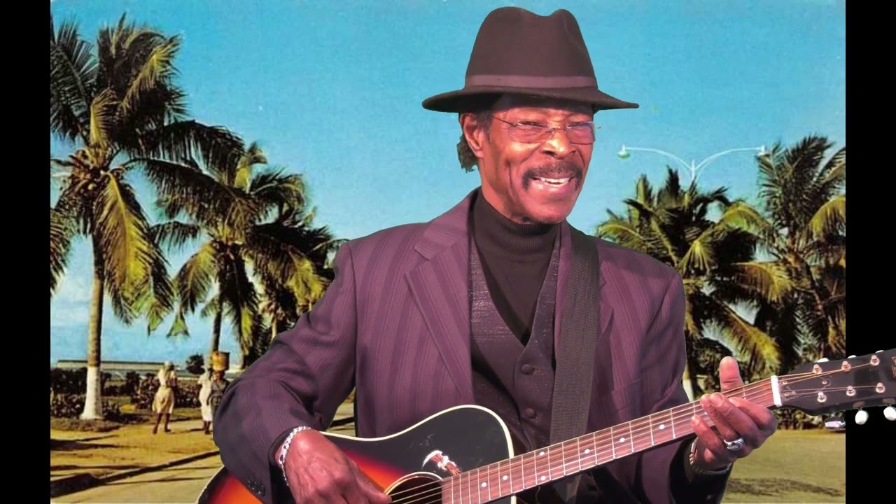 Roman Paul playing guitar against a tropical backdrop from a Haiti film
