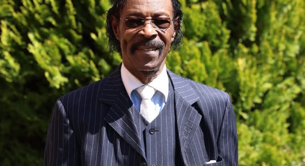 Roman Paul smiling in a pinstripe suit, photographed outdoors
